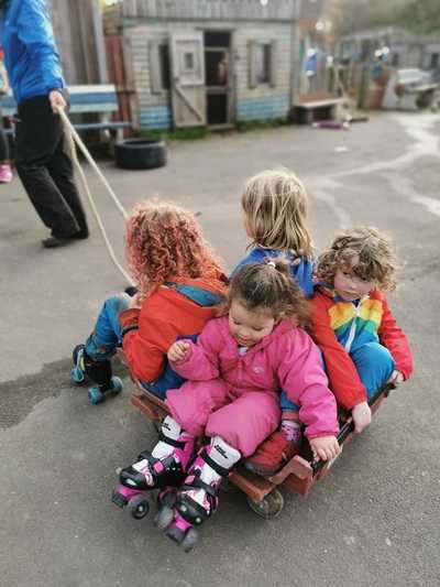 Four children are enjoying being pulled around on a bread tray with castors