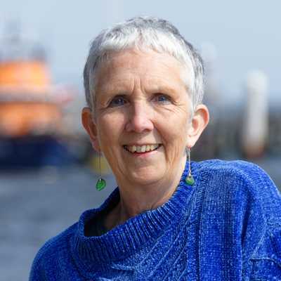 Ann Cleeves in a blue jumper with a body of water in the background